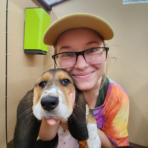 A person smiling while holding a puppy